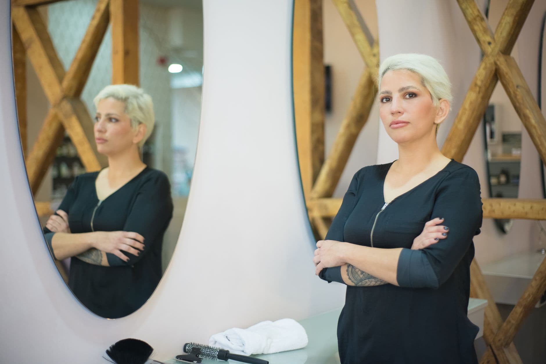 Właścicielka salonu fryzjerskiego stojąca przy lustrze